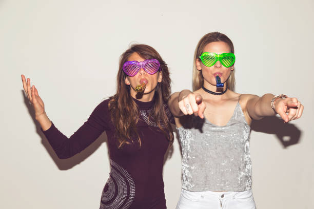 Two girl friends having fun, dancing and making crazy faces while taking photos at a party