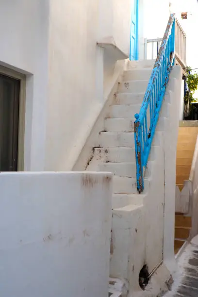 Photo of One of the charms of Mykonos, Greek island in the heart of the Cyclades, are its narrow staircases to access white houses with small flowered balconies touching almost above the cobblestone streets