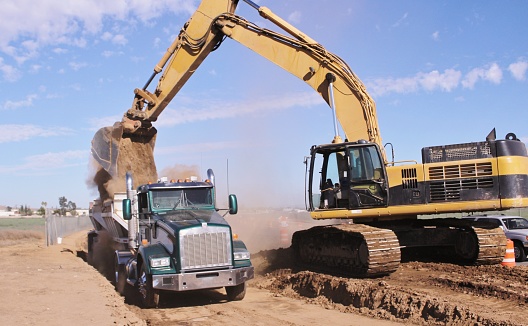 Excavator Removing Dirt and Loading into a Bottom Dump Truck in Perris California