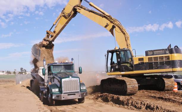 Excavator Removing Dirt and Loading into a Bottom Dump Truck in Perris California Excavator Removing Dirt and Loading into a Bottom Dump Truck in Perris California dump truck photos stock pictures, royalty-free photos & images