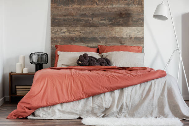 istock Comfortable king size bed with wooden rustic headboard and white industrial lamp next to it 1159452405