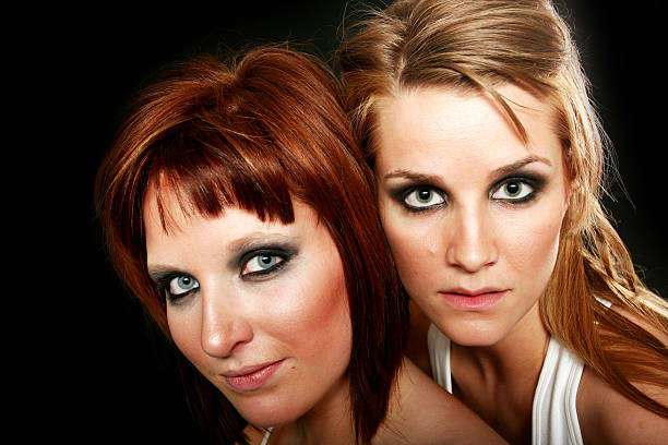 Two young girl friends standing together and having fun. Looking at camera.
