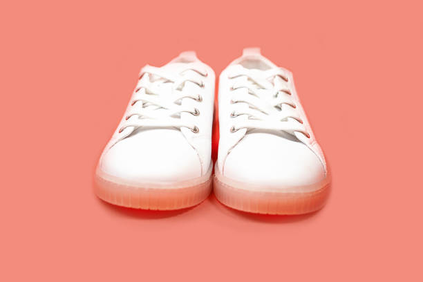 istock White sneakers are lying on a pastel pink coral background. 1159453471