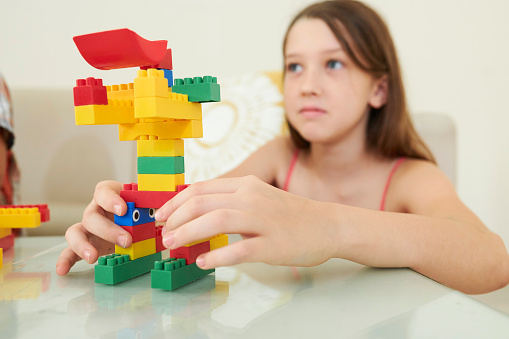 Robot made of colorful plastic bricks in hands of preteen girl at craft class
