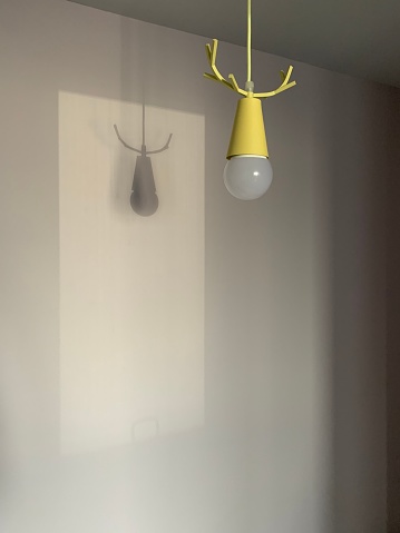 Yellow lamp with horns. Shadow on the wall.