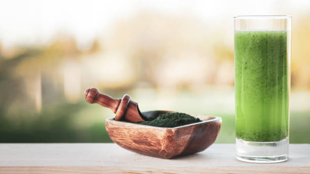 зеленый смузи со спирулиной на деревянном фоне - barley grass juice green стоковые фото и �изображения