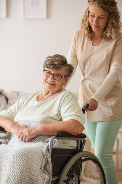 istock Positive senior patient on wheelchair with supportive nurse 1159458036