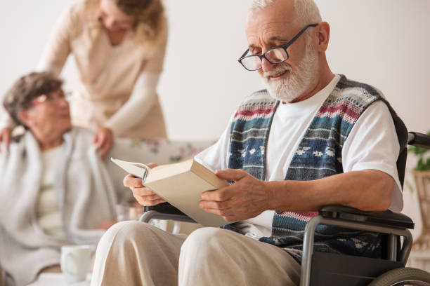 istock Senior man on wheelchair reading a book 1159458042