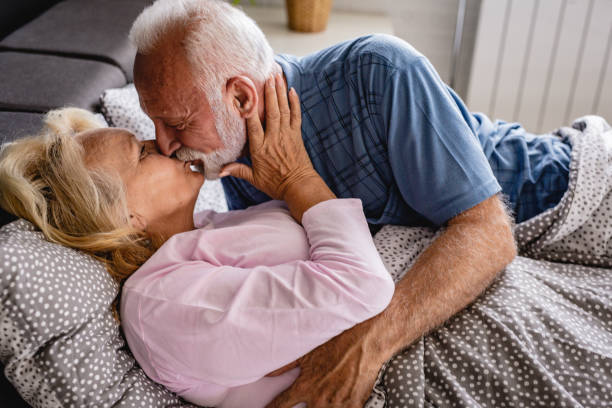 the old senior couple are kissing in bed - romance sensuality couple bed imagens e fotografias de stock