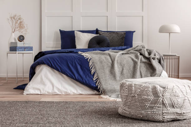 istock Velvet round pillow on king size bed with blue and white sheets 1159461435
