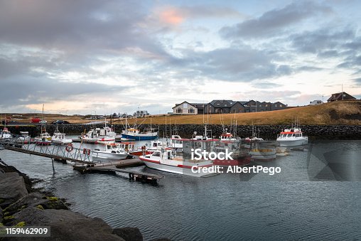 istock Fishing boat in a small harbour at sunset 1159462909