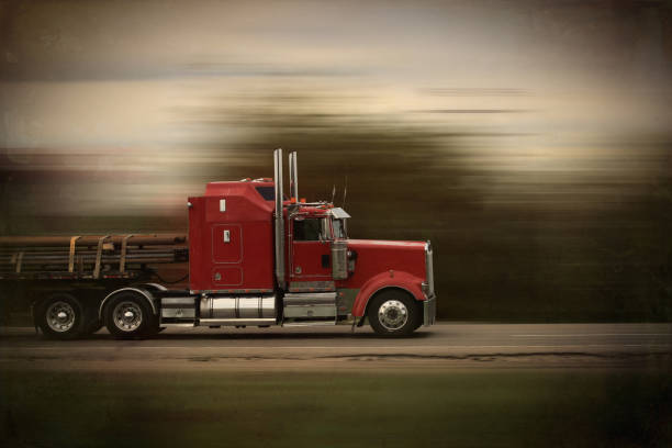 Bright red modern big rig semi truck and trailer in motion on a highway