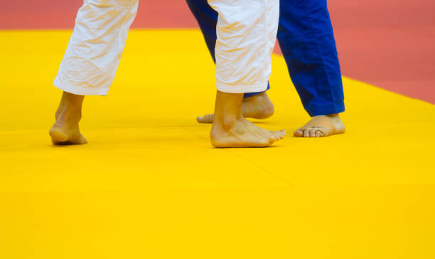 zwei judo-kämpfer in weiß-blauer uniform. - tatami matte stock-fotos und bilder