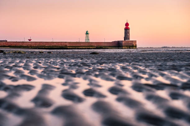 Harbor entrance on the German North Sea coast at dusk with silt in the foreground.