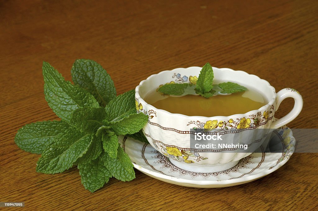 mint tea in floral teacup on wood table Mint tea is used as a refreshing drink and herbal medicine. This is spearmint. Also Spearmint Stock Photo