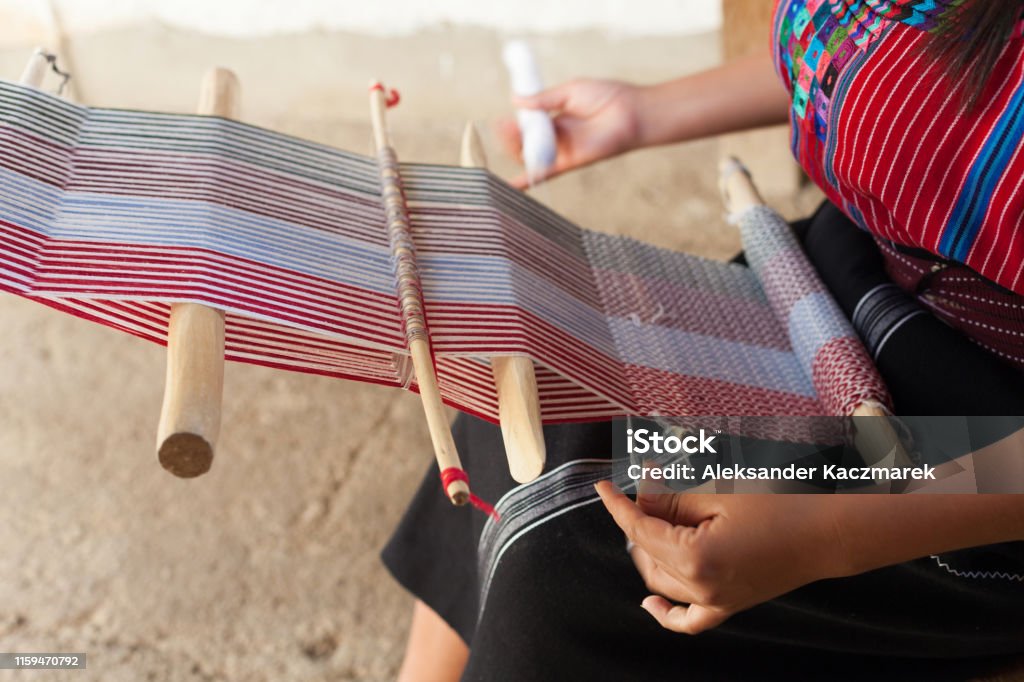 Hands Of A Woman Weaving On An Old Wooden Loom Close up of hands of a woman weaving on an old wooden loom. Guatemala Stock Photo