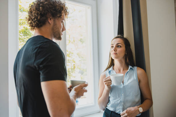 istock Young couple drinking coffee in their new apartment and talking 1159474043