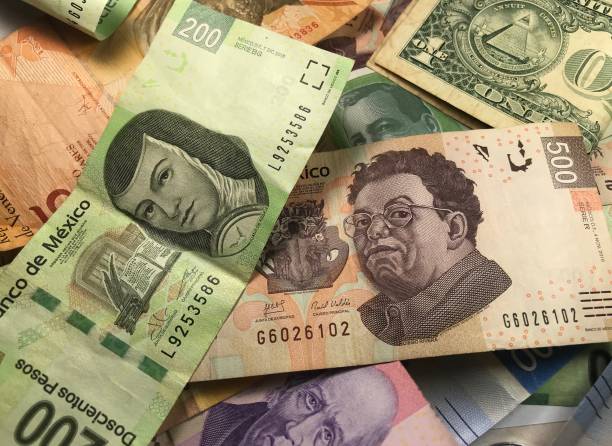 istock Many mixed Mexican peso bills spread over a wooden desk 1159477343