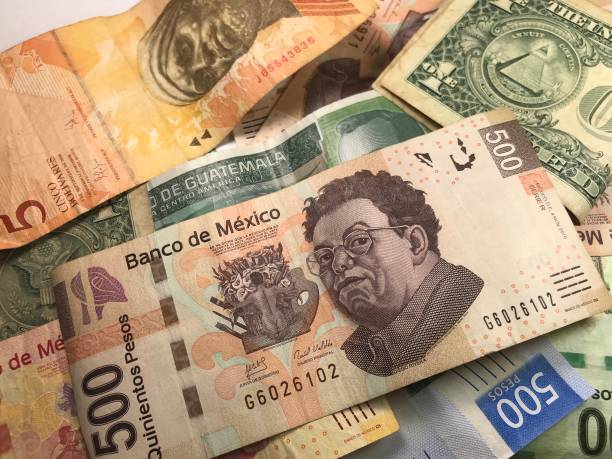 istock Many mixed Mexican peso bills spread over a wooden desk 1159477344