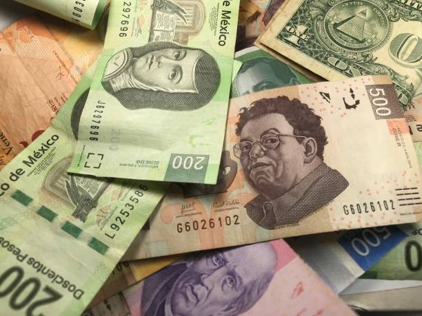 istock Many mixed Mexican peso bills spread over a wooden desk 1159477348