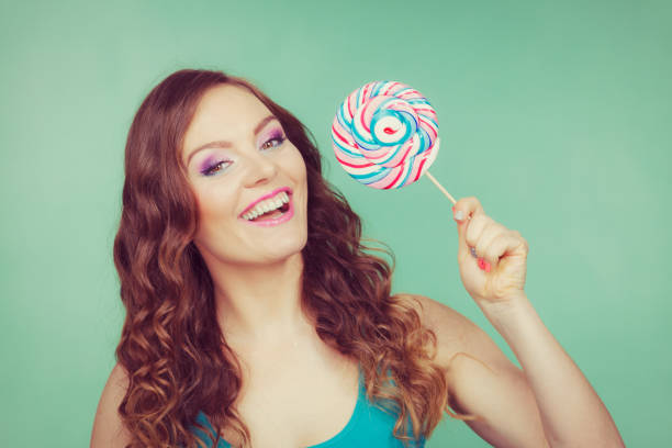 istock Smiling girl with lollipop candy on teal 1159477409