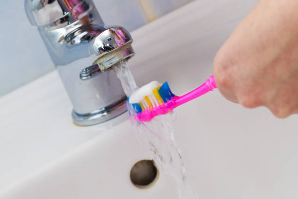 istock Hand holding toothbrush in bathroom 1159479194