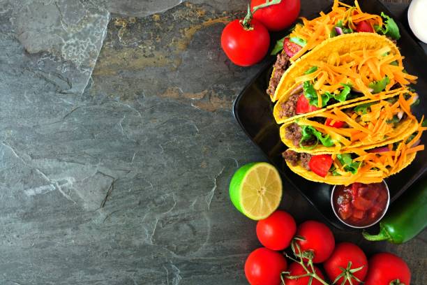 istock Hard shelled tacos, top view, side border on a dark background with copy space 1159484187