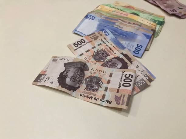 istock Many mexican pesos bills spread over a beige colored desk inside a small business office 1159485181