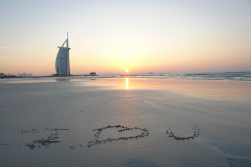 VIew of Burja Al Arab the iconic Dubai 7 star luxury hotel at sunset time. I Love You text carved in the golden sands of Jumairah beach in the focus