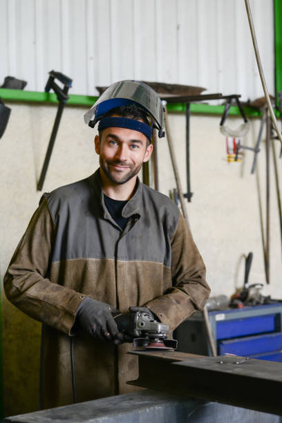 istock handsome man workshop grinding iron spark fire hot steel with power tool and protective gear 1159495185