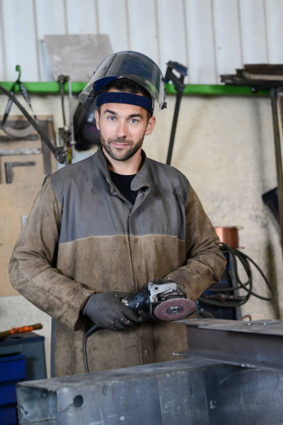 istock handsome man workshop grinding iron spark fire hot steel with power tool and protective gear 1159495186