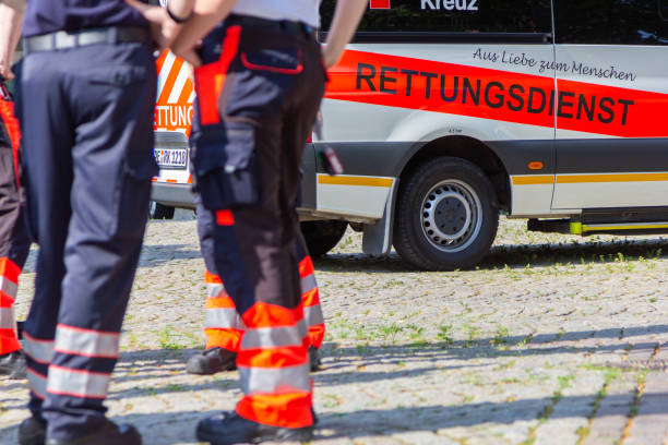 l'ambulancier paramédical féminin allemand se tient devant une voiture d'ambulance. - ambulance healthcare and medicine germany car photos et images de collection