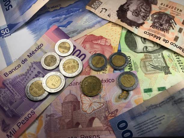 istock Many mixed Mexican peso bills spread over a wooden desk 1159498681