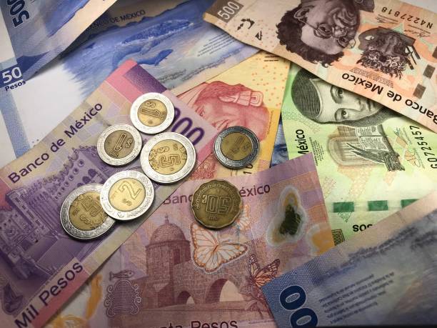 istock Many mixed Mexican peso bills spread over a wooden desk 1159498695