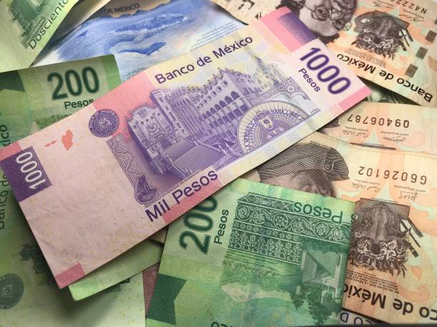 istock Many mixed Mexican peso bills spread over a wooden desk 1159498707
