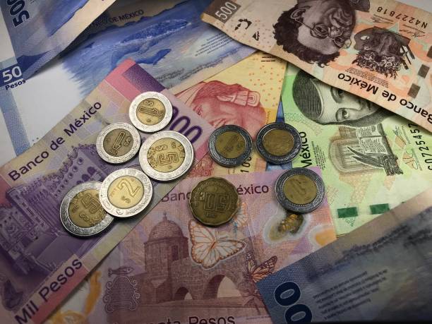 istock Many mixed Mexican peso bills spread over a wooden desk 1159498708