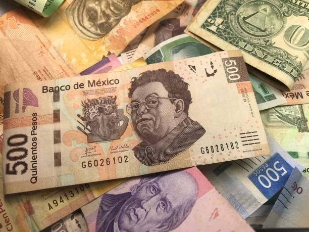 istock Many mixed Mexican peso bills spread over a wooden desk 1159498738