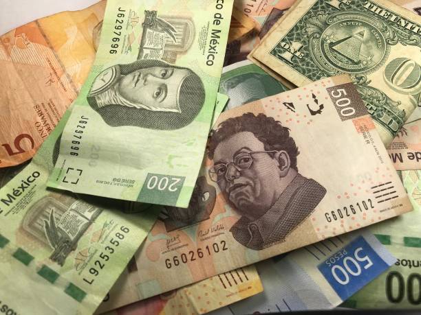 istock Many mixed Mexican peso bills spread over a wooden desk 1159498759