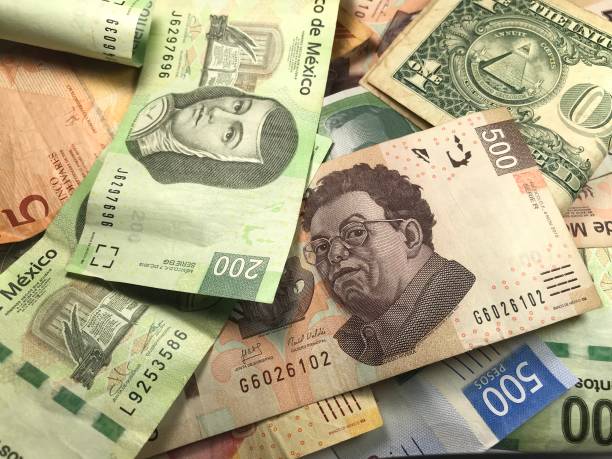 istock Many mixed Mexican peso bills spread over a wooden desk 1159498768