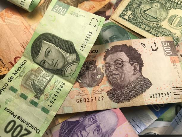 istock Many mixed Mexican peso bills spread over a wooden desk 1159498786