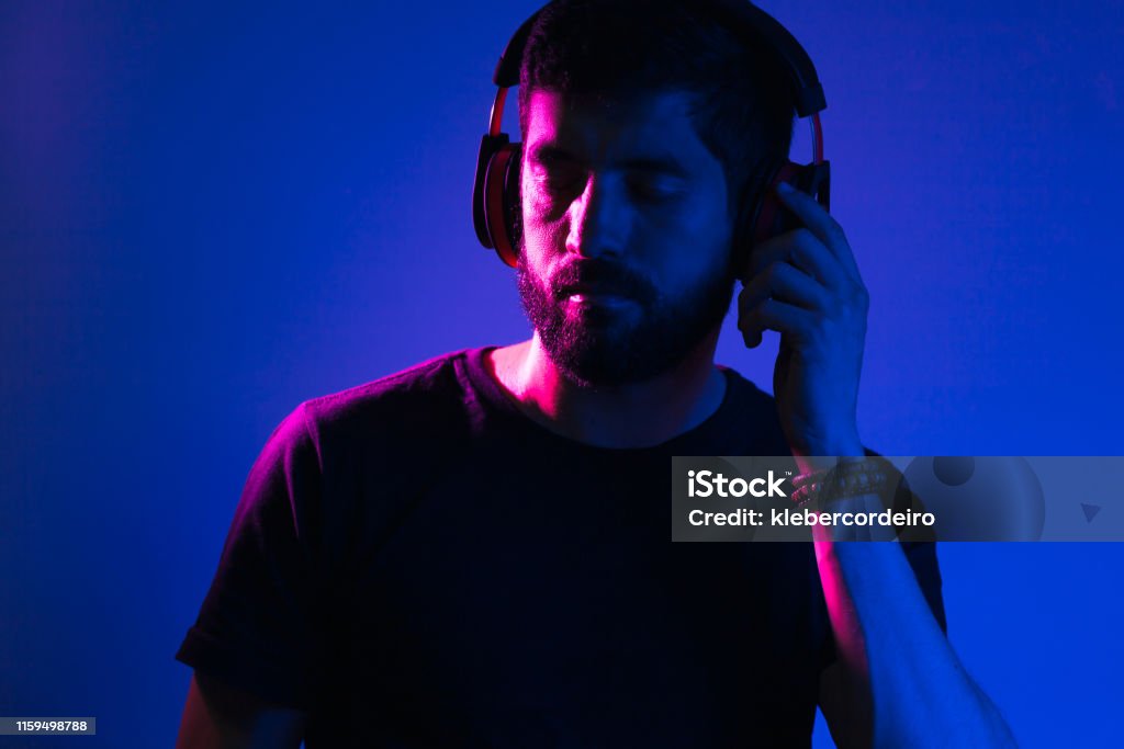 Retrato de luz de neón de hombre barbudo en auriculares. Escuchar música - Foto de stock de Letrero de neón libre de derechos