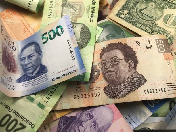 istock Many mixed Mexican peso bills spread over a wooden desk 1159498798