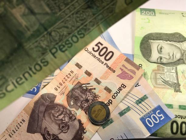istock Many mixed Mexican peso bills spread over a wooden desk 1159498800