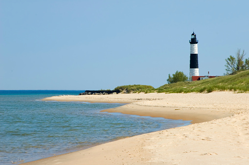 Lighthouse overlooking the beach, water, and sand along the shore of Lake Michigan, 