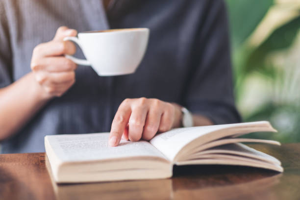 istock a woman pointing and reading a book while drinking coffee 1159508033