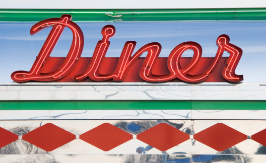 Diner sign in red neon at a roadside restaurant, close up, retro americana in vintage style, USA.