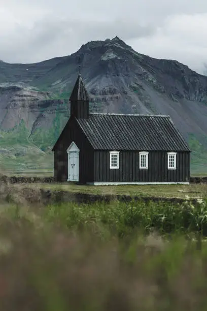 Photo of Famous black church of Budir at Snaefellsnes peninsula region in Iceland. Amazing rocks and mountain view on background. Autumn in Iceland.