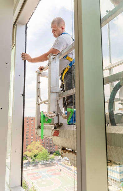 istock The man, blue-collar worker replacing a broken window in the office building - cleaning the frame after the old broken glass has been removed. High-altitude work on the lifting platform which is placed outside. 1159523586