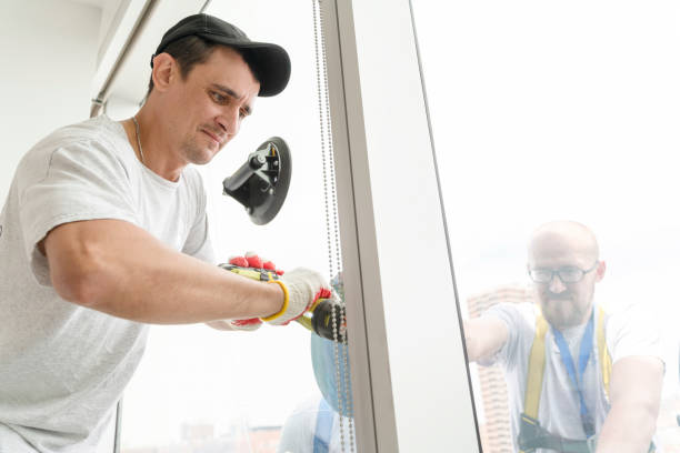 istock Team of blue-collar workers replacing a broken window in the office building - removing the old broken glass. High-altitude work on the lifting platform which is placed outside. 1159523598