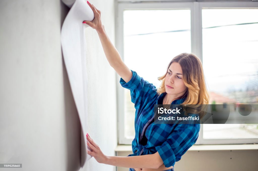 Young woman choosing house wallpaper Young couple getting ready for home remodeling Wallpaper - Decor Stock Photo